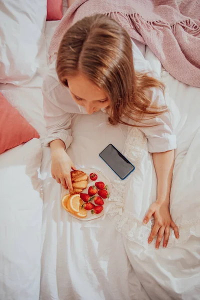 Girl taking photo of plate with strawberries, top view — Stock Photo, Image