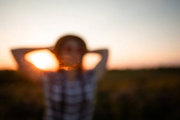 Rozmazaný obraz mladé dívky na pozadí západu slunce — Stock fotografie