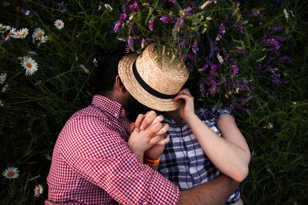 Романтическая пара, обнимающаяся в летнем поле с цветущими полевыми цветами — стоковое фото