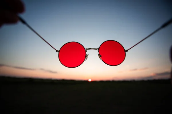 Par de gafas rojas sobre fondo de cielo al atardecer — Foto de Stock