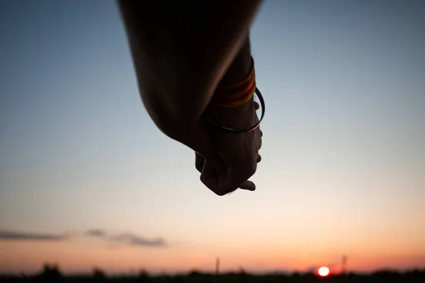 Couple romantique tenant la main dans le champ d'été au coucher du soleil — Photo