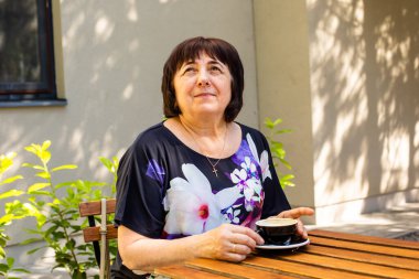 Yaşlı kadın caddedeki kafede dinleniyor.