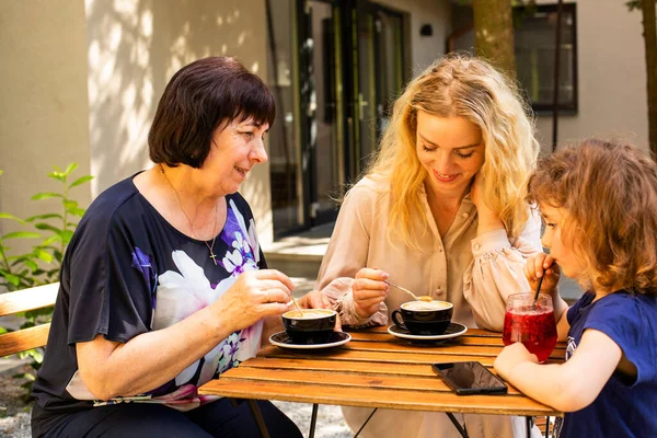 Mormor, dotter och barnbarn vilar på ett gatucafé. — Stockfoto