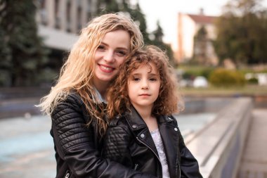 Anne ve kızı bir kasaba meydanında oturuyorlar.