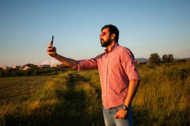 Mutlu genç adam yaz tarlasında selfie çekiyor.