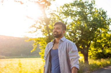 Neşeli genç adam köy yolunda yürüyor.