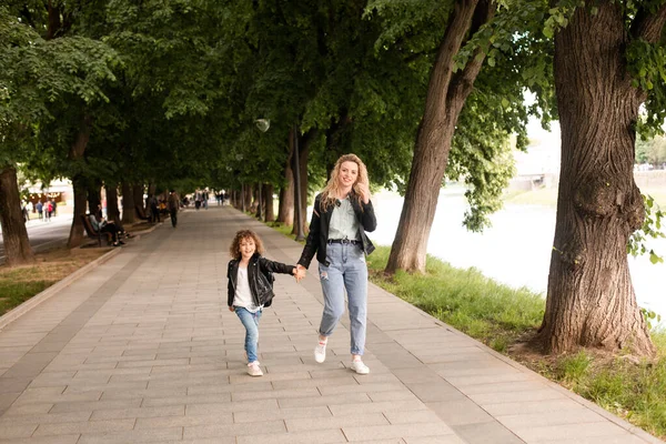 Máma a holčička chodí po městě a drží se za ruce. — Stock fotografie