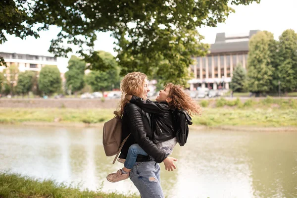 The daughter kisses her mom while walking in the waterfront — Stock Photo, Image