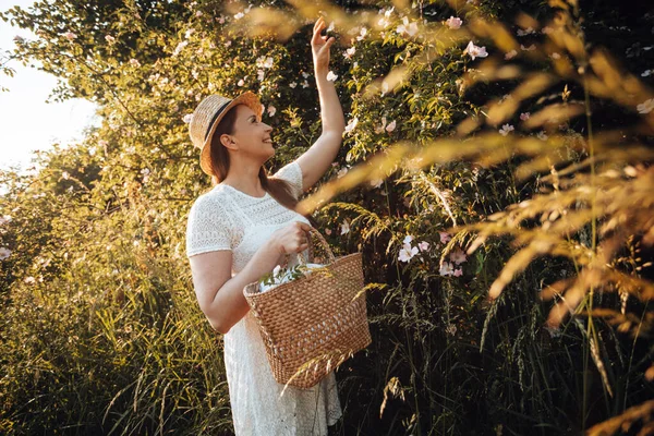 Mulher bonita no chapéu segurando cesta com flores — Fotografia de Stock