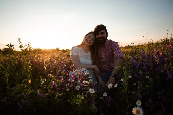 Romantický pár, sedící na louce, objímající venku — Stock fotografie