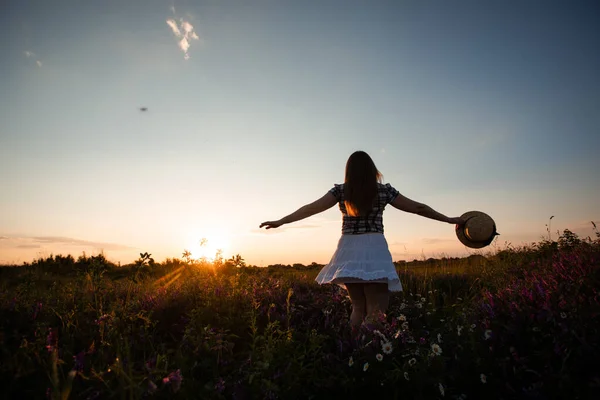 Dívka těší svobodu sledování západu slunce na louce — Stock fotografie