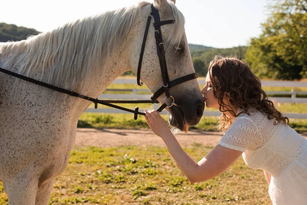 De vrouw met krullend haar huddles aan haar paard — Stockfoto