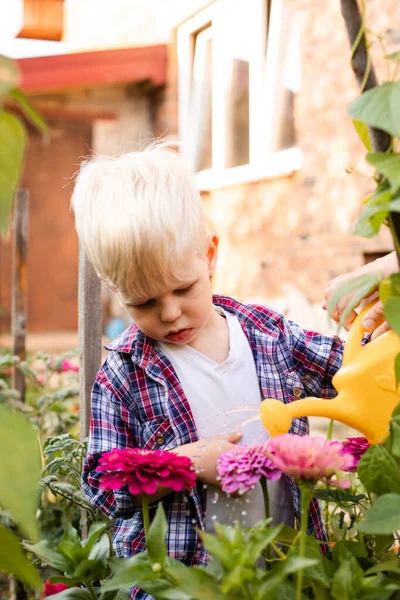 幼児は散水缶を使用して庭の花に散水しています — ストック写真