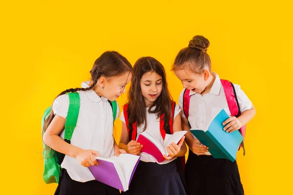 De kleine schoolmeisjes lezen de boeken op de gele achtergrond — Stockfoto