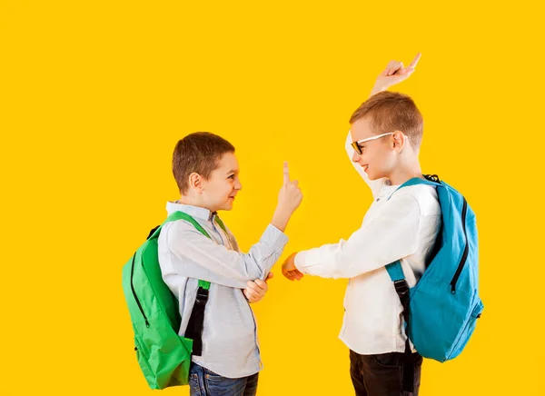 Estudantes bonitos em uniforme com mochilas no fundo amarelo — Fotografia de Stock