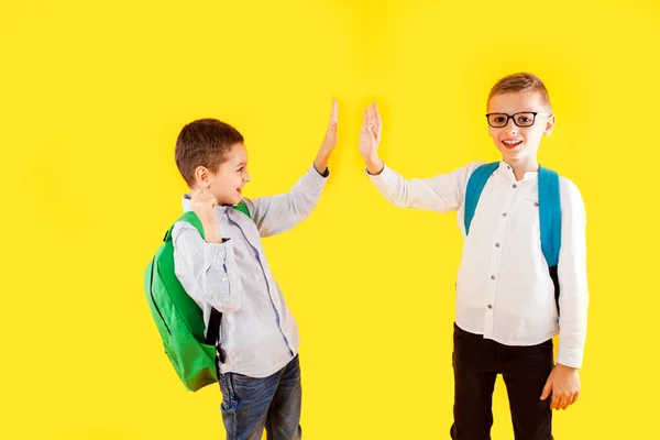 Прыжки эмоциональных школьников на жёлтом фоне — стоковое фото