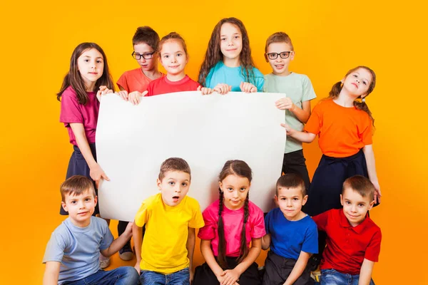 Die Gruppe von Kindern hält ein großes weißes Kopierraum-Plakat in der Hand — Stockfoto