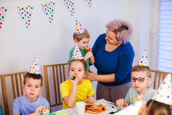 Stödjande mor hjälpa liten pojke att blåsa party horn — Stockfoto