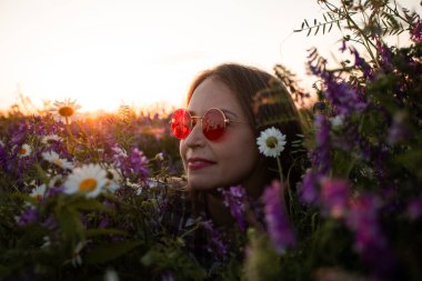 Çiçekler arasında kırmızı gözlüklü kadının sanatsal portresi