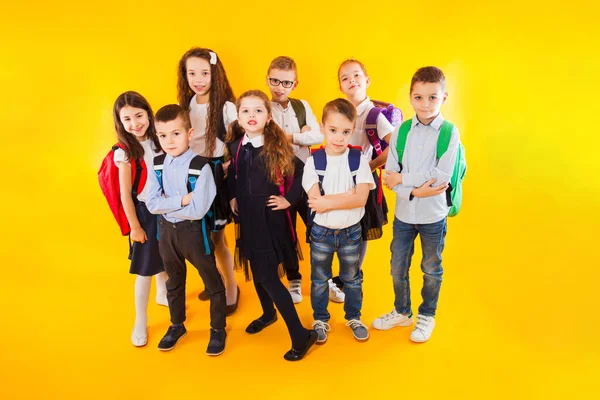 Die freundlichen Klassenkameraden umarmen sich auf gelbem Hintergrund — Stockfoto