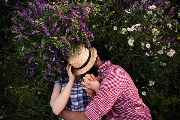 Romantiskt par omfamnar på sommarfältet med blommande vilda blommor — Stockfoto