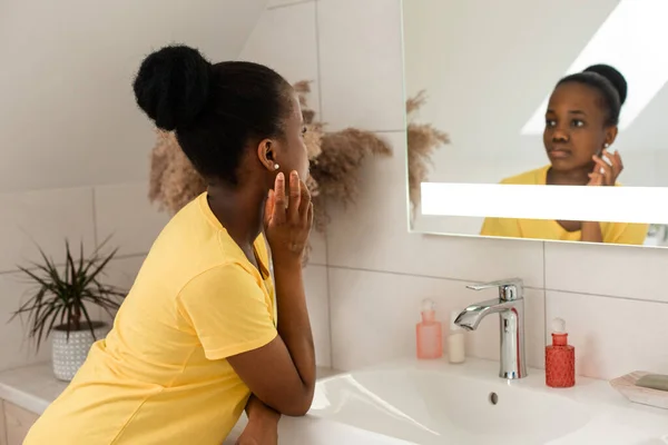 Mörk flådd flicka tittar in i spegeln berörande kinder — Stockfoto