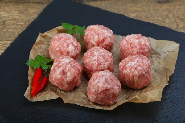 Raw meatballs on wooden chopping board — Stock Photo, Image