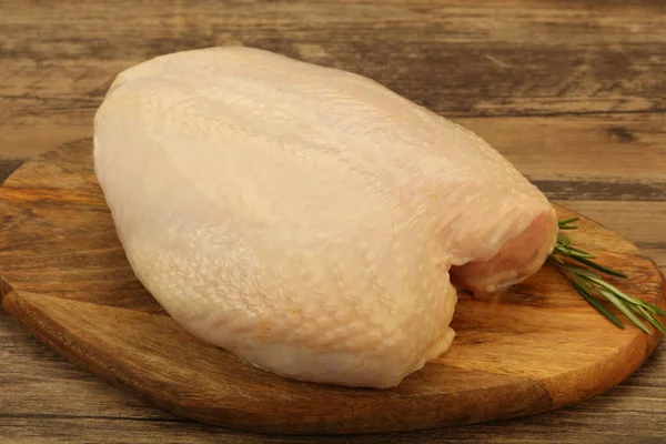 Raw whole chicken breast with skin served rosemnary