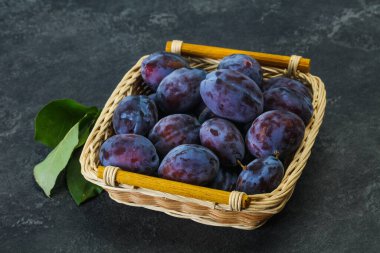 Olgun erik yığını sepetin içinde yapraklarla