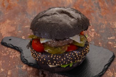 Peynirli ve sebzeli lezzetli siyah hamburger.