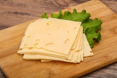 Salata yapraklarının üzerinde dilimlenmiş sarı peynir.