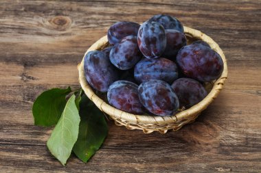 Olgun erik yığını sepetin içinde yapraklarla