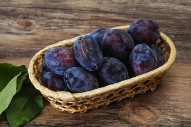 Olgun erik yığını sepetin içinde yapraklarla