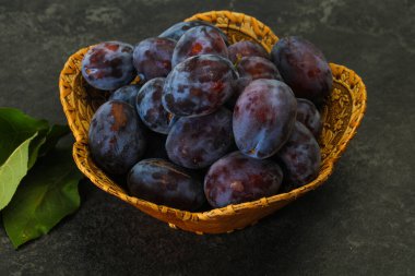 Olgun erik yığını sepetin içinde yapraklarla