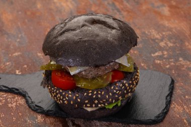 Peynirli ve sebzeli lezzetli siyah hamburger.