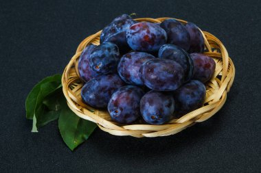 Olgun erik yığını sepetin içinde yapraklarla