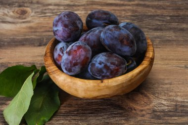 Olgun erik yığını sepetin içinde yapraklarla