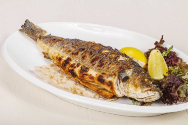 Izgara deniz kabuğu balığı limon ve salata servis etti.