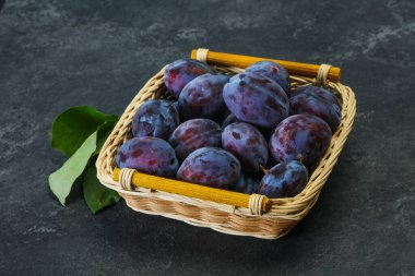 Olgun erik yığını sepetin içinde yapraklarla