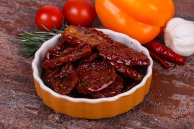 Kavanozda kurutulmuş domates, zeytinyağı biberiye, salata yaprakları ve sarımsak.