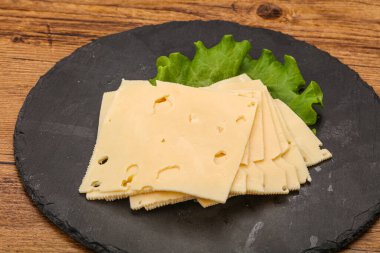 Salata yapraklarının üzerinde dilimlenmiş sarı peynir.