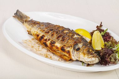 Izgara deniz kabuğu balığı limon ve salata servis etti.