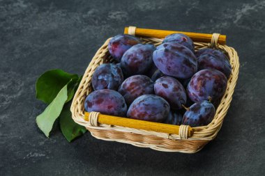 Olgun erik yığını sepetin içinde yapraklarla