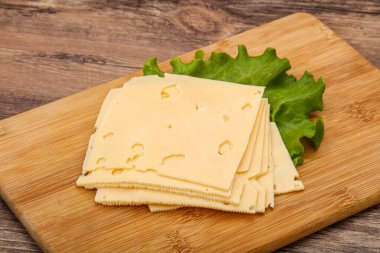 Salata yapraklarının üzerinde dilimlenmiş sarı peynir.