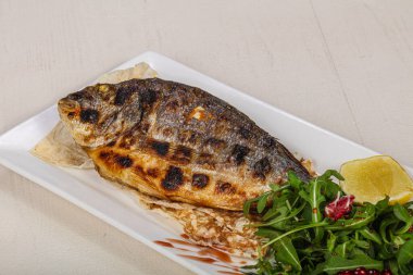 Kızarmış dorada balığı limon ve roka servis etti.
