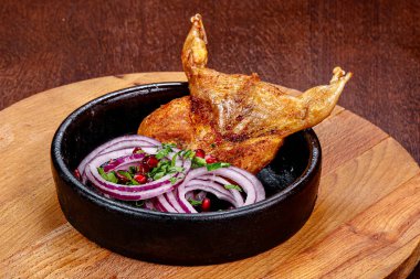 Kavrulmuş bıldırcın tencerede soğan halkaları servis edildi.