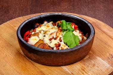 Kavrulmuş domuz eti ve kabında peynir olan sebzeler.