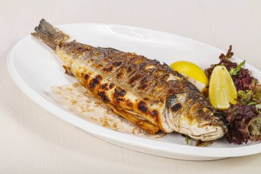 Izgara deniz kabuğu balığı limon ve salata servis etti.