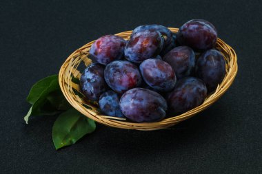 Olgun erik yığını sepetin içinde yapraklarla