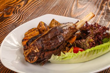 Pişmiş kuzu budu, sebze ve salata yapraklı.